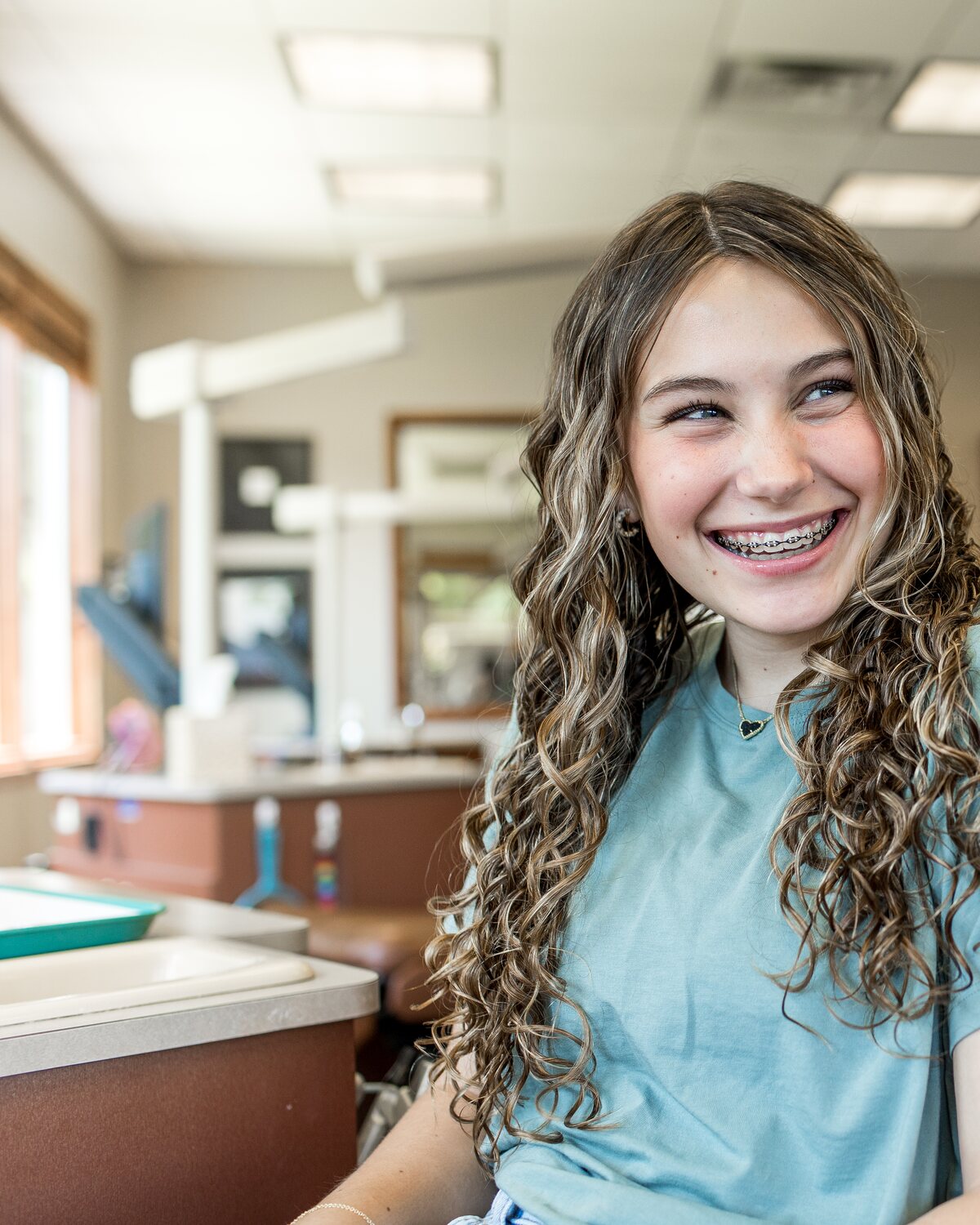 A teenage patient with braces smiling in a treatment chair at the practice.