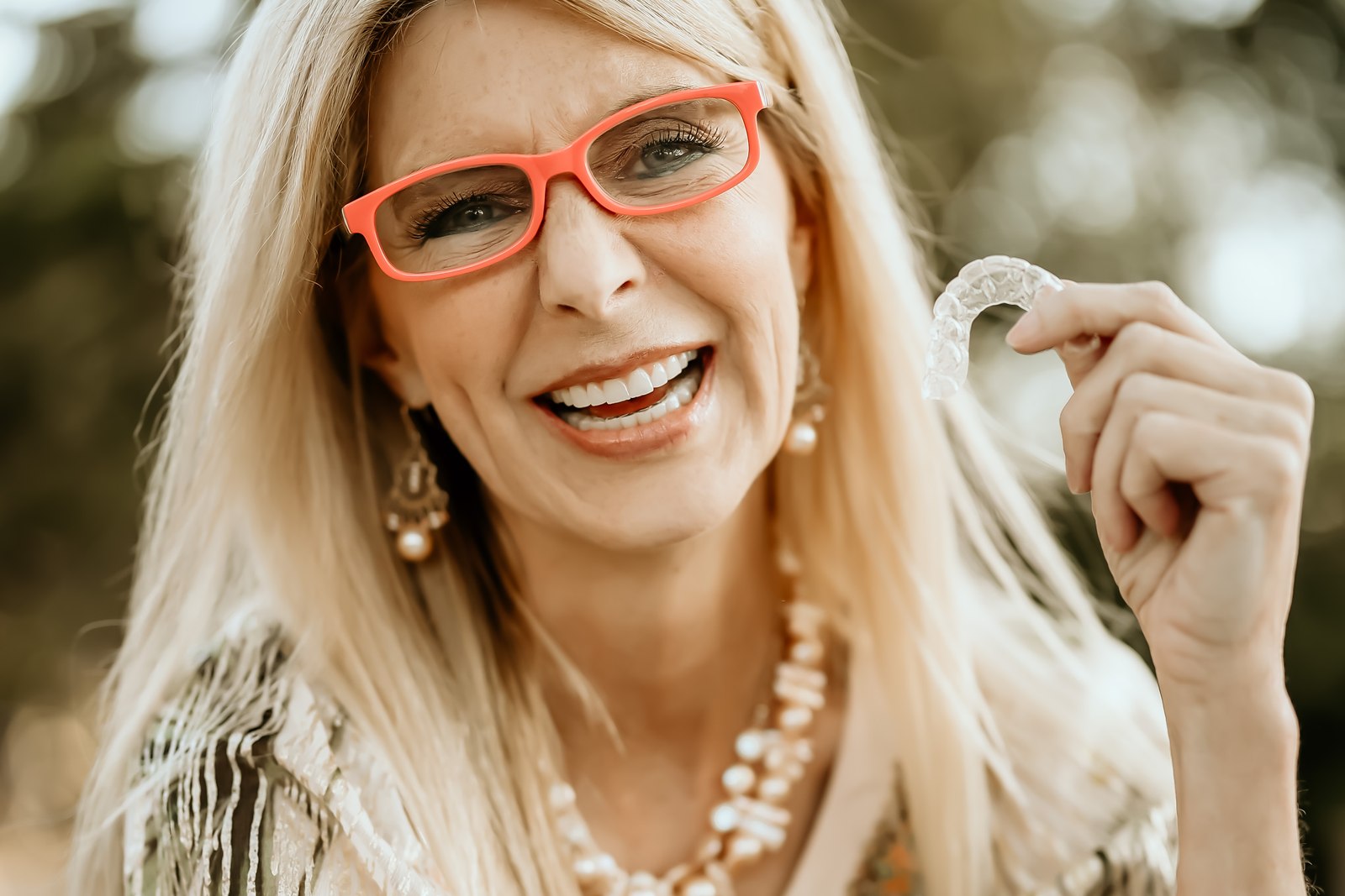An adult patient holding one of her clear aligners.