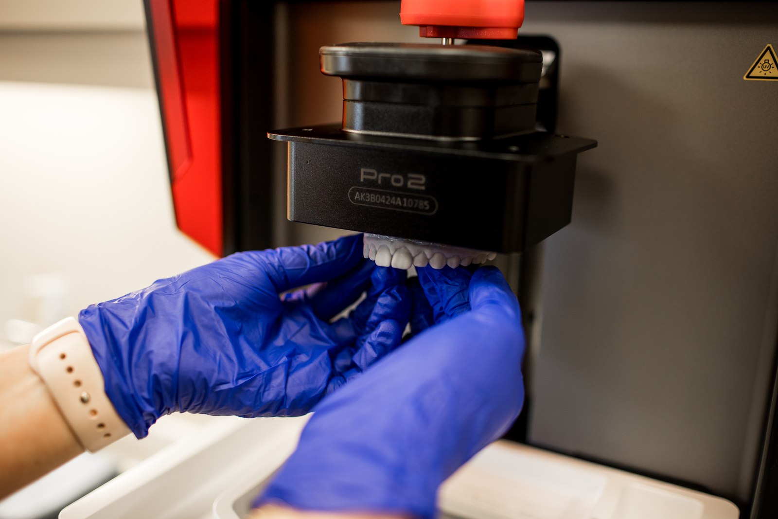 A printed dental model being lifted from the practice's 3D printer.