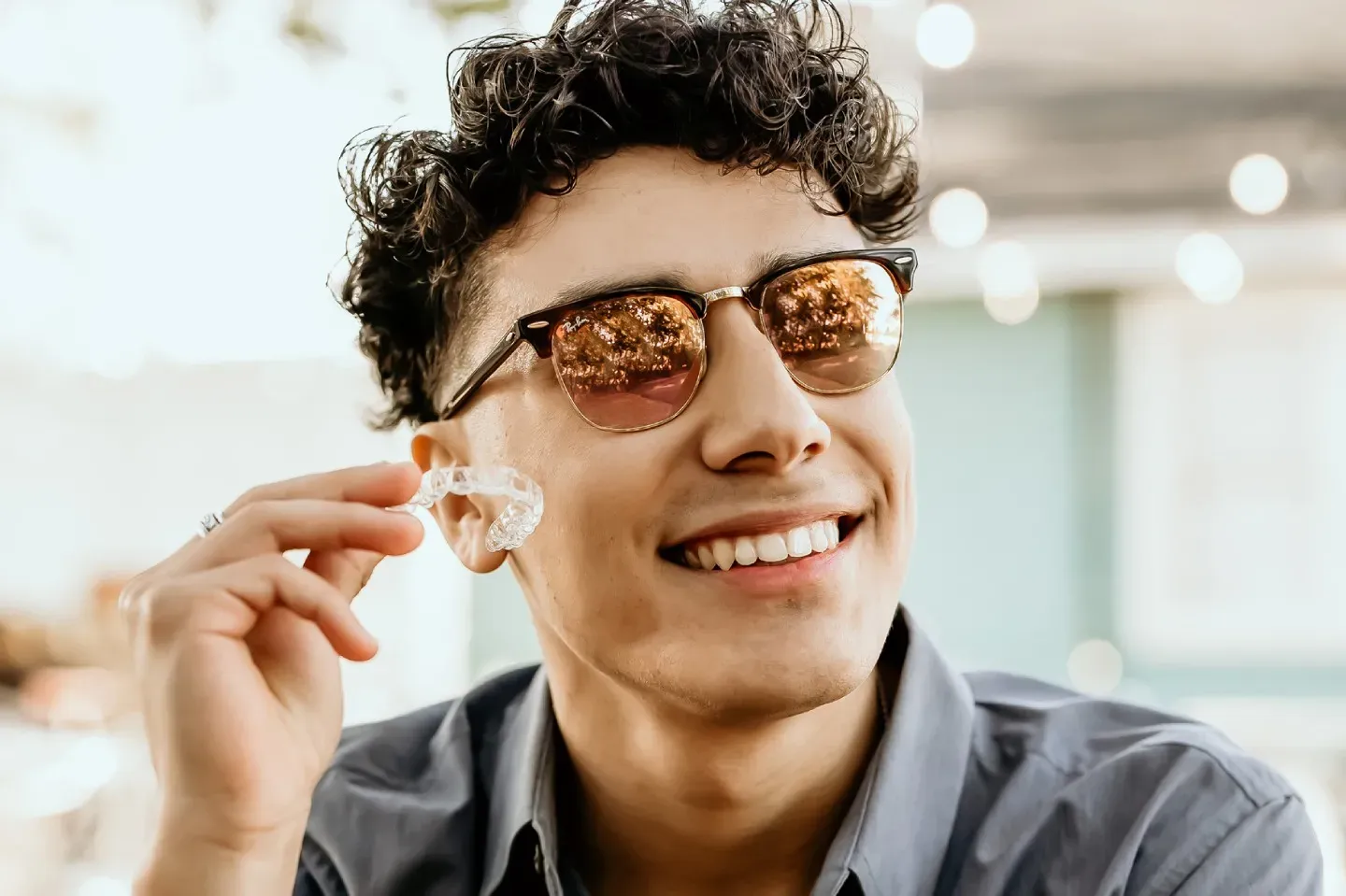 Un paciente con lentes sostiene un alineador transparente.