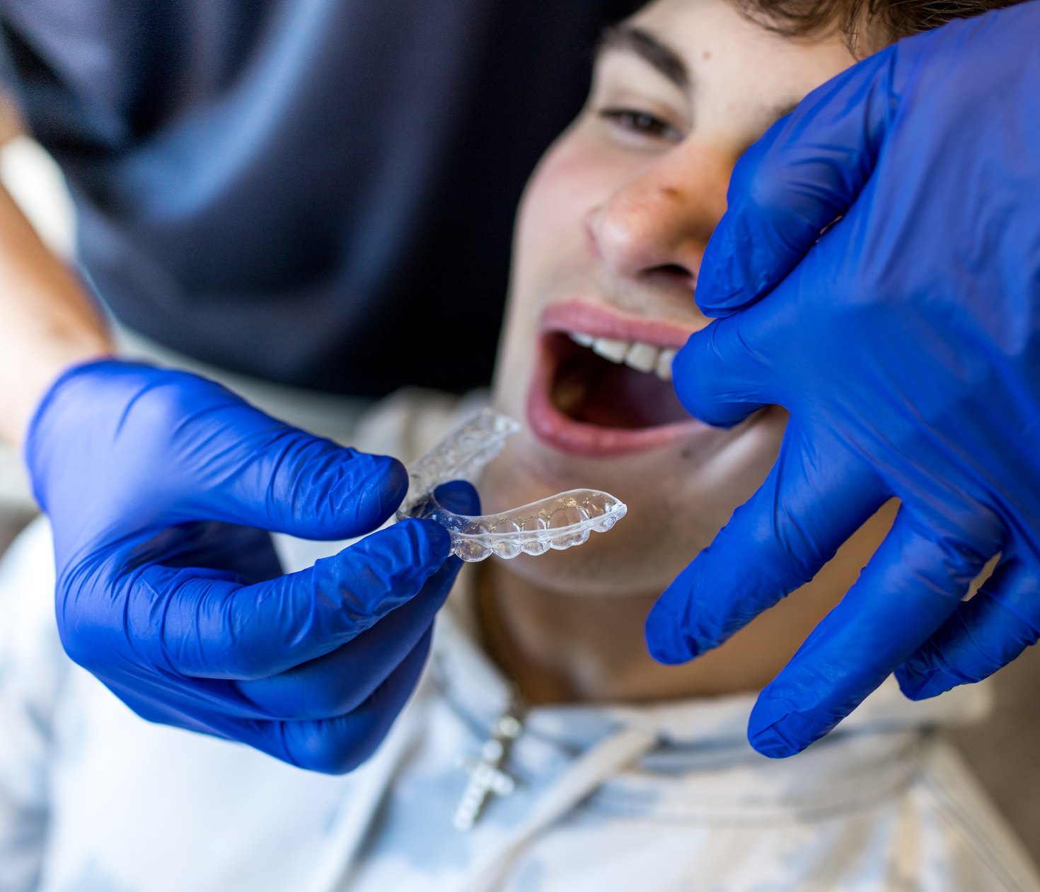 An orthodontic assistant fitting a clear aligner tray for a patient.